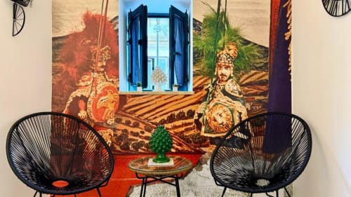 Elegante lounge di appartamento a Palermo con due sedie uovo nere, tavolino rosso, decorazioni murali raffinate e finestra blu affacciata