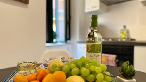 Accoglienza in cucina con vino bianco, uva fresca e agrumi in un appartamento di Palermo con elettrodomestici moderni