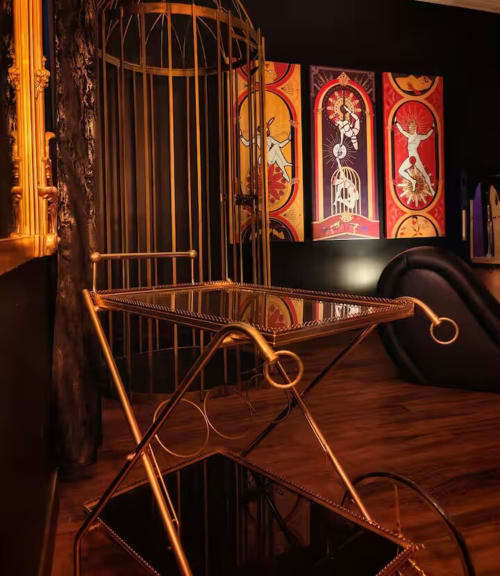 Golden birdcage-inspired furniture with ornate art panels at La Maison Defendue hotel in Tessy-Bocage