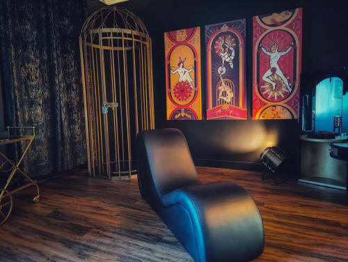 Modern lounge area at La Maison Defendue with vibrant artwork, sculptural chair, and brass birdcage in Tessy-Bocage