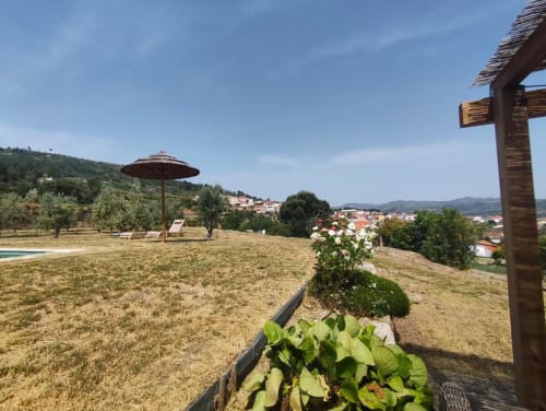 Jardim ensolarado da villa SM Stays Collection em Guarda com vistas rurais, guarda-sol, espreguiçadeiras e vegetação exuberante