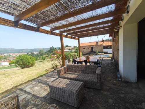 Terraço sombreado da villa SM Stays Collection em Guarda, Portugal com móveis de vime e vistas para a paisagem rural