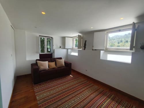 Sala de estar da villa moderna na SM Stays Collection em Guarda com sofá escuro, tapete listrado e vista do jardim através de grandes janelas