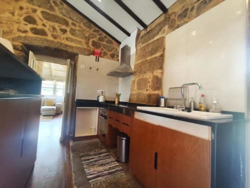 Cozinha moderna com armários em terracota, paredes de pedra e claraboia na villa SM Stays, Guarda Portugal