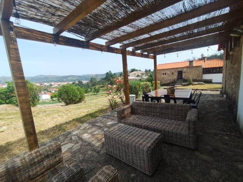 Pérgula com cobertura e mobiliário em vime com vista para a paisagem rural de Guarda na Quinta de Gonçalo, Portugal
