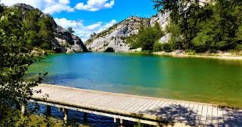Lac alpin turquoise avec ponton en bois, montagnes rocheuses et forêts verdoyantes près de Saint-Rémy-de-Provence