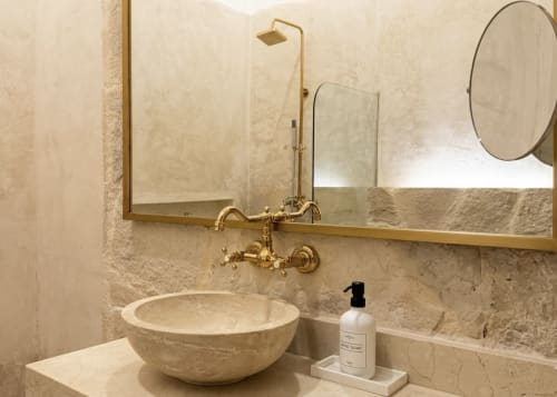 Baño de lujo en Villa Merida Boutique Hotel con lavamanos de piedra, griferías de bronce y espejos elegantes.