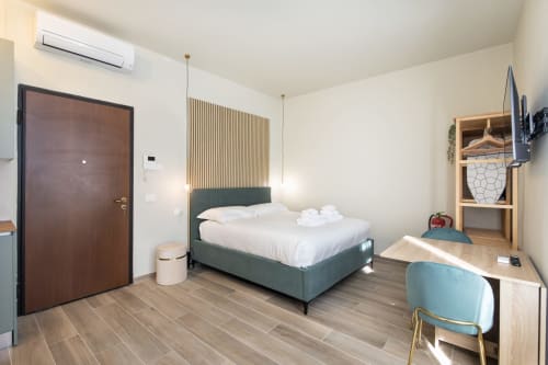 Modernes Schlafzimmer in den Magnolia Apartments Mailand mit grünem Bett, Holzschreibtisch, Stadtblick und zeitgenössischen Möbeln
