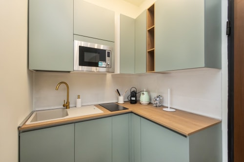 Moderne Küche in Magnolia Apartments Mailand mit mintgrünen Schränken, Holzarbeitsplatten, Edelstahlspüle und Einbaugeräten