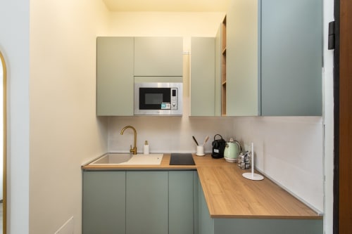 Moderne Küche in Magnolia Apartments Mailand mit Salbeigrünen Schränken, Holzarbeitsplatte und integriertem Mikrowellenherd