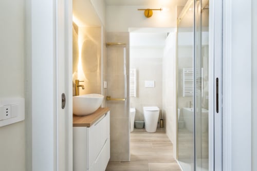 Modernes Badezimmer in den Magnolia Apartments Mailand mit Aufsatzwaschbecken, Toilette und begehbarer Dusche mit Glaseinfassung