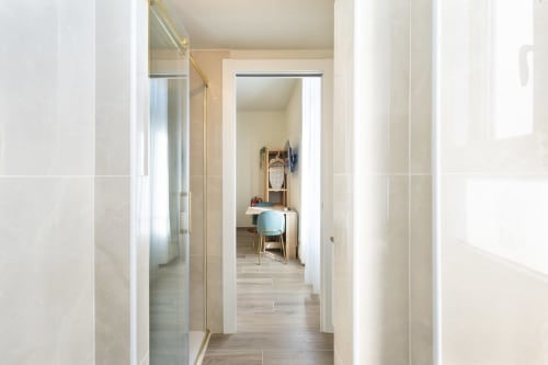Moderner Flur in den Magnolia Apartments Mailand mit Fliesenbelag, weißen Wänden und Blick in möbliertes Zimmer