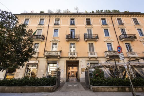 Fassade der Magnolia Apartments Mailand, historisches cremebeiges Gebäude mit schmiedeeisernen Balkonen in der Orti Center Straße