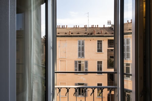 Blick aus einem Mailänder Apartmentfenster auf pfirsichfarbene Hofgebäude mit Ziegeldächern