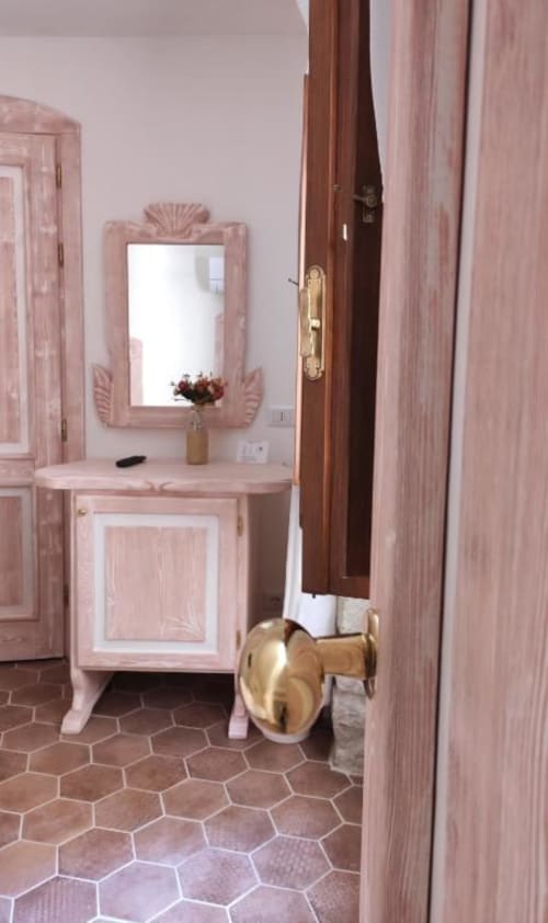 Vanity in legno rosa con specchio e dettagli dorati nella suite Regnos Altos, Bosa Italia