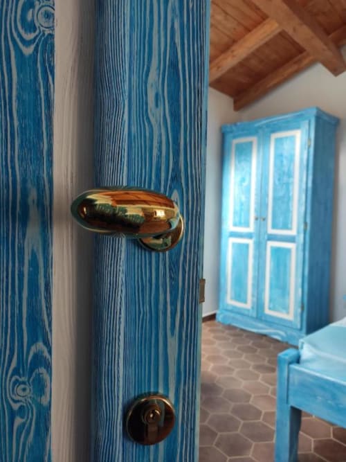 Porta in legno blu con maniglia in ottone nella suite di Bosa, guardaroba visibile