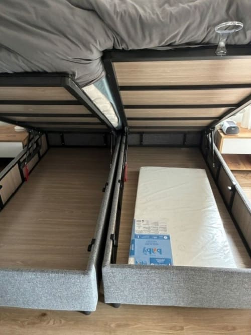 Opened storage bed frame with mattress at ALMA ROSSA hotel in Lecci, showing wood slats and gray upholstered base