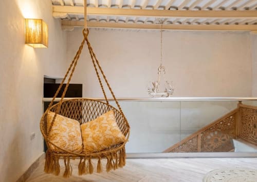 Silla colgante tejida con cojines dorados en la Chambre 4 del Villa Merida Boutique Hotel, Mérida