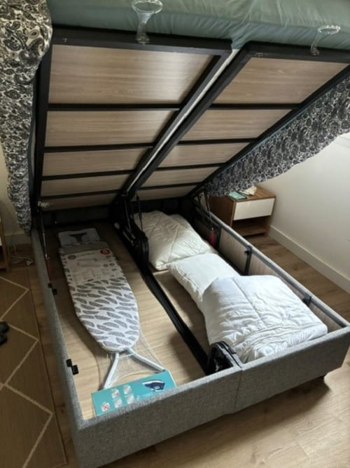 Storage bed with white bedding and ironing board at ALMA ROSSA hotel in Lecci