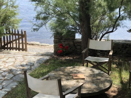 Salon de plage à la villa La Conciergerie du Cap Corse avec chaises, terrasse en pierre, fleurs rouges et vue sur mer à Centuri