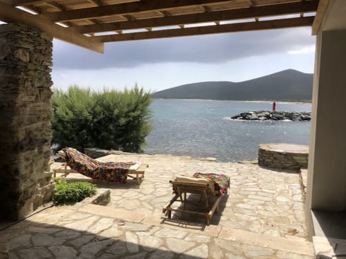 Terrasse en bord de mer de la villa Domaine Robinson à Centuri, Corse avec des transats face à la mer turquoise et aux montagnes
