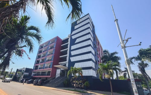 Modern Cozy Apartments Ghana building in Ridge, Accra with red and blue facade, palm trees, and city views, featuring shared