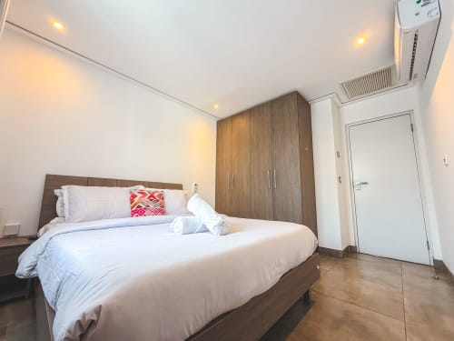 Modern bedroom in Ridge Apartment at Cozy Apartments Ghana with queen bed, wooden wardrobe, and air conditioning.