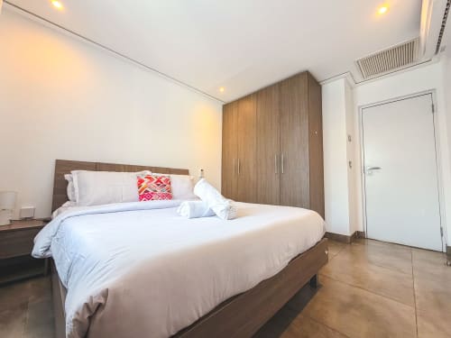 Modern bedroom in Ridge Apartment at Cozy Apartments Ghana with queen bed, wooden wardrobe, white linens, and wooden flooring