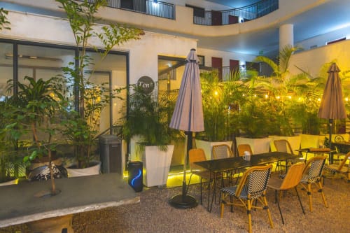 Cozy Apartments Ghana courtyard with dining area, tropical plants, umbrellas, and warm lighting at night in Accra