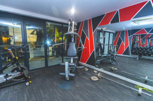 Modern gym at Cozy Apartments Ghana with cardio equipment, weights, and mirrored walls in Accra