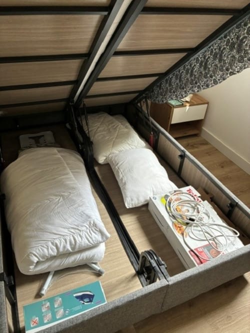 Upscale storage bed at ALMA ROSSA, Lecci showing white pillows, quilts, and belongings organized in open compartments.