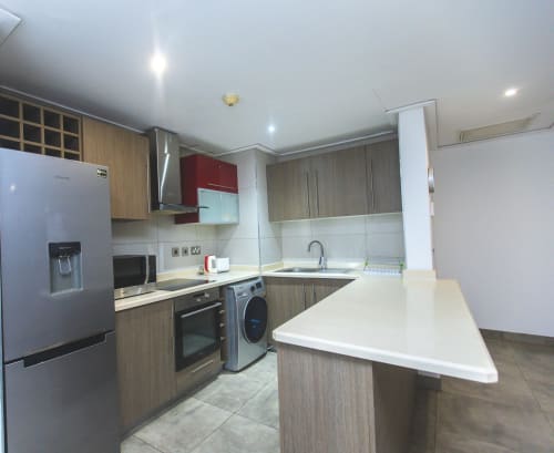 Modern kitchen in Ridge Apartment at Cozy Apartments Ghana featuring wooden cabinets, stainless steel appliances, white