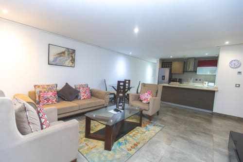 Modern living room in Ridge Apartment, Cozy Apartments Ghana with beige sofa, dining table, and open kitchen area