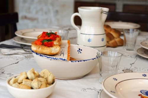 Elegante mise en place da Trulli Boccadoro con stoviglie color crema, decori floreali blu, dolci freschi con frutti di bosco e