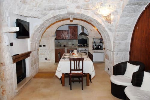 Appartamento Trulli Boccadoro con 2 camere: zona pranzo con soffitto in pietra ad arco, cucina, camino e posti a sedere