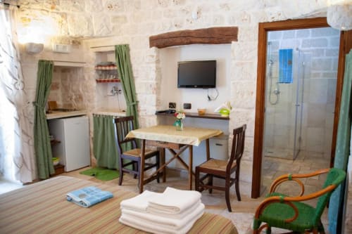 Monolocale a Trulli Boccadoro con tavolo da pranzo, angolo cottura, TV e bagno nella campagna italiana
