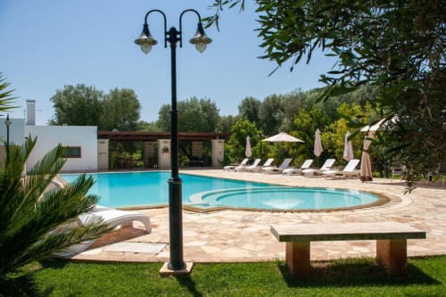 Area piscina di Trulli Boccadoro con lettini, ombrelloni e ulivi nella campagna italiana