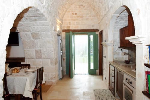 Cucina rustica in pietra con soffitti a volta, porte verdi, camino e zona pranzo - Appartamento Trullo 2 camere