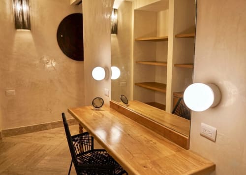 Tocador moderno con encimera de madera, espejos iluminados y silla negra en habitación del Hotel Villa Merida Boutique, Merida