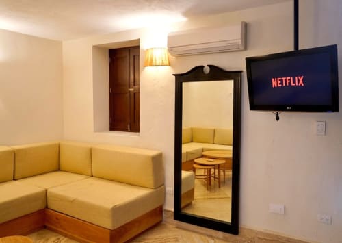 Sofá esquinero amarillo brillante con TV en la Habitación 4 de Villa Merida Boutique Hotel, Merida, con espejo y comodidades modernas