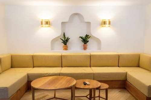 Elegante sala de estar en Villa Merida Boutique Hotel con sofá seccional amarillo, mesas de madera y apliques de pared modernos en Mérida