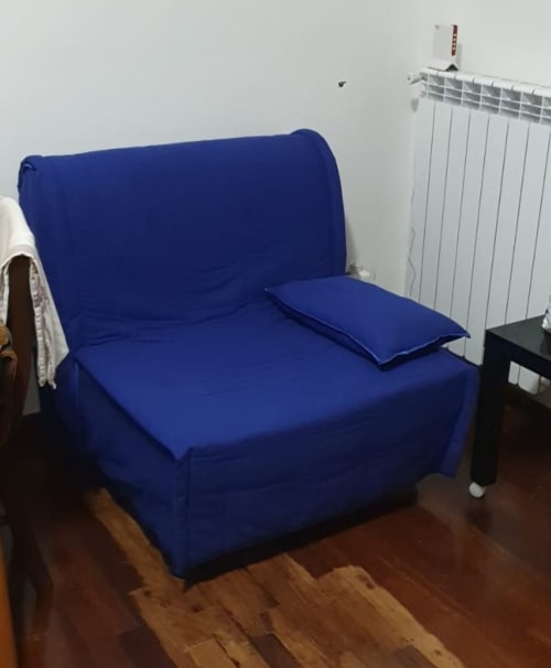 Poltrona blu con cuscino in appartamento romano, con radiatore bianco e pavimento in legno