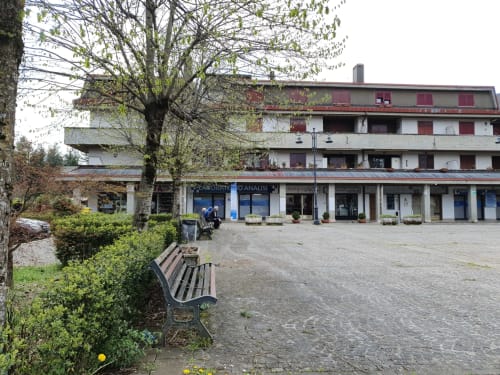 Cortile dell'hotel Myob a Roma con panchine, negozi e edificio residenziale con persiane