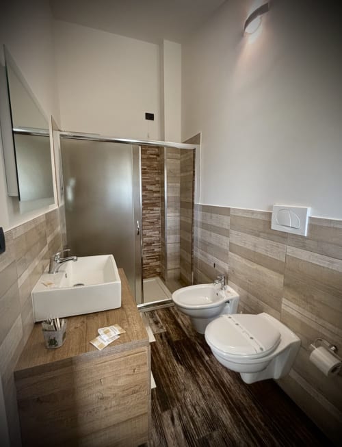 Bagno moderno presso il B&B Hélios a Nardò con wc, bidet, lavabo e cabina doccia con rivestimenti in piastrelle marroni