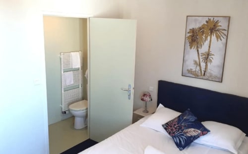 Chambre Double aux Genêts d'Or avec lit noir, draps blancs, salle de bain privée et décoration palmette