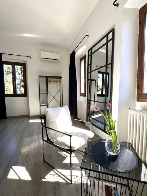 Camera moderna a La Dolce Casa B&B a Cremia con letto in ferro battuto nero, specchio, cuscini bianchi e tulipani rosa