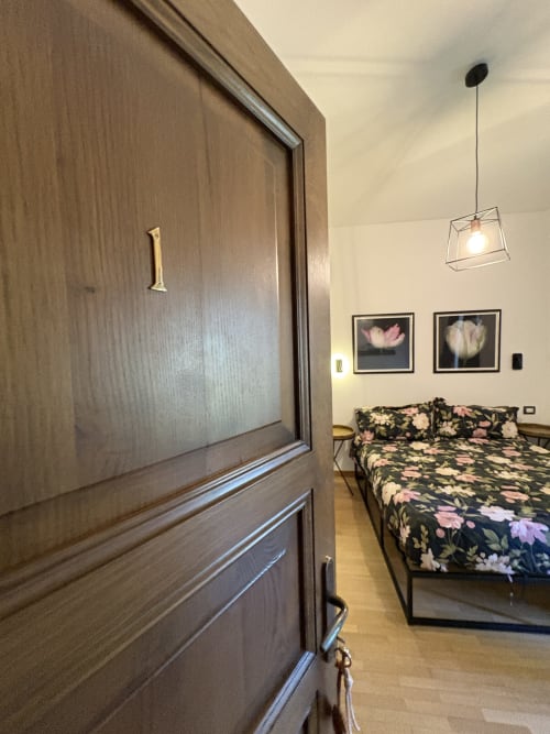 Camera moderna a La Dolce Casa B&B a Cremia con biancheria floreale, lampada a sospensione e quadri con fiori