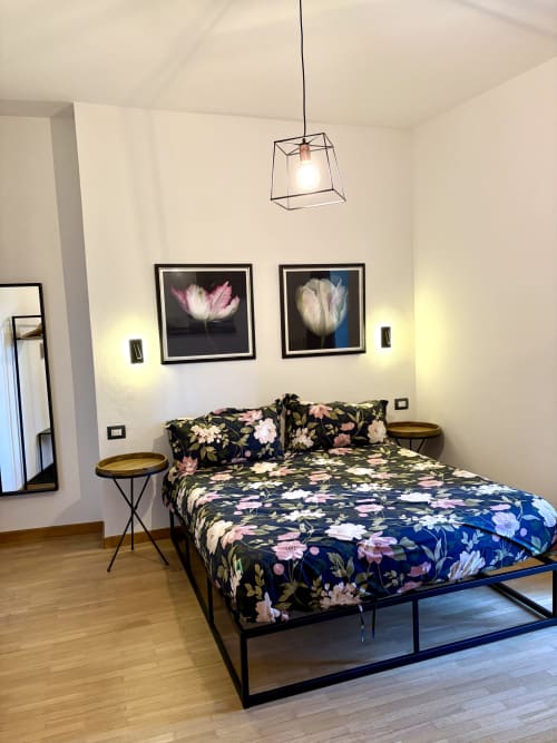 Modern bedroom at La Dolce Casa B&B in Cremia with floral bedding, framed flower artwork, pendant light, and wooden flooring.