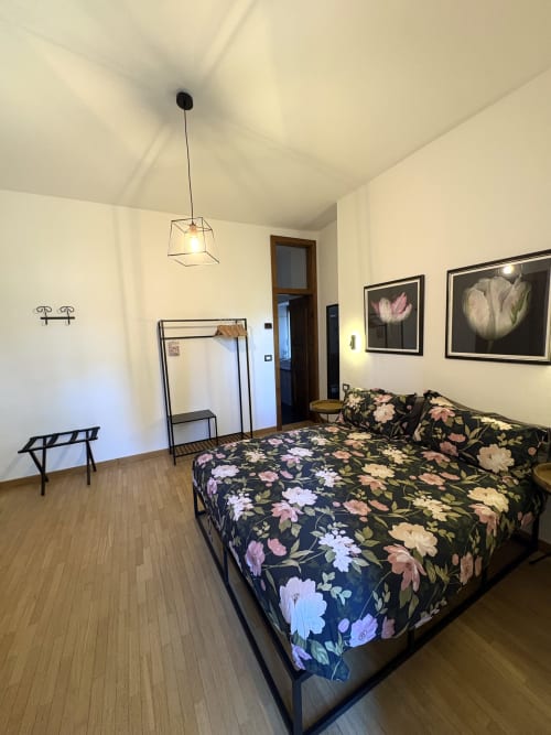 Modern bedroom at La Dolce Casa B&B in Cremia with floral bedding, pendant light, and framed flower artwork
