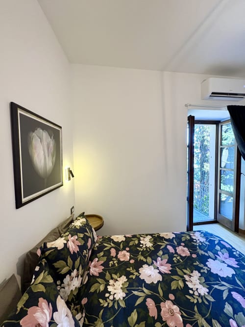 Bedroom at La Dolce Casa in Cremia with floral bedding, lake view balcony, and AC unit
